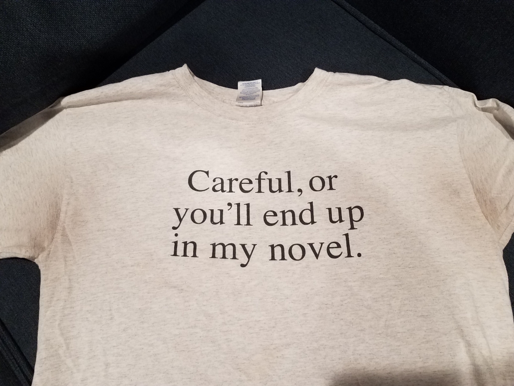 Picture of a gray tshirt that says "Careful, or you'll end up in my novel."